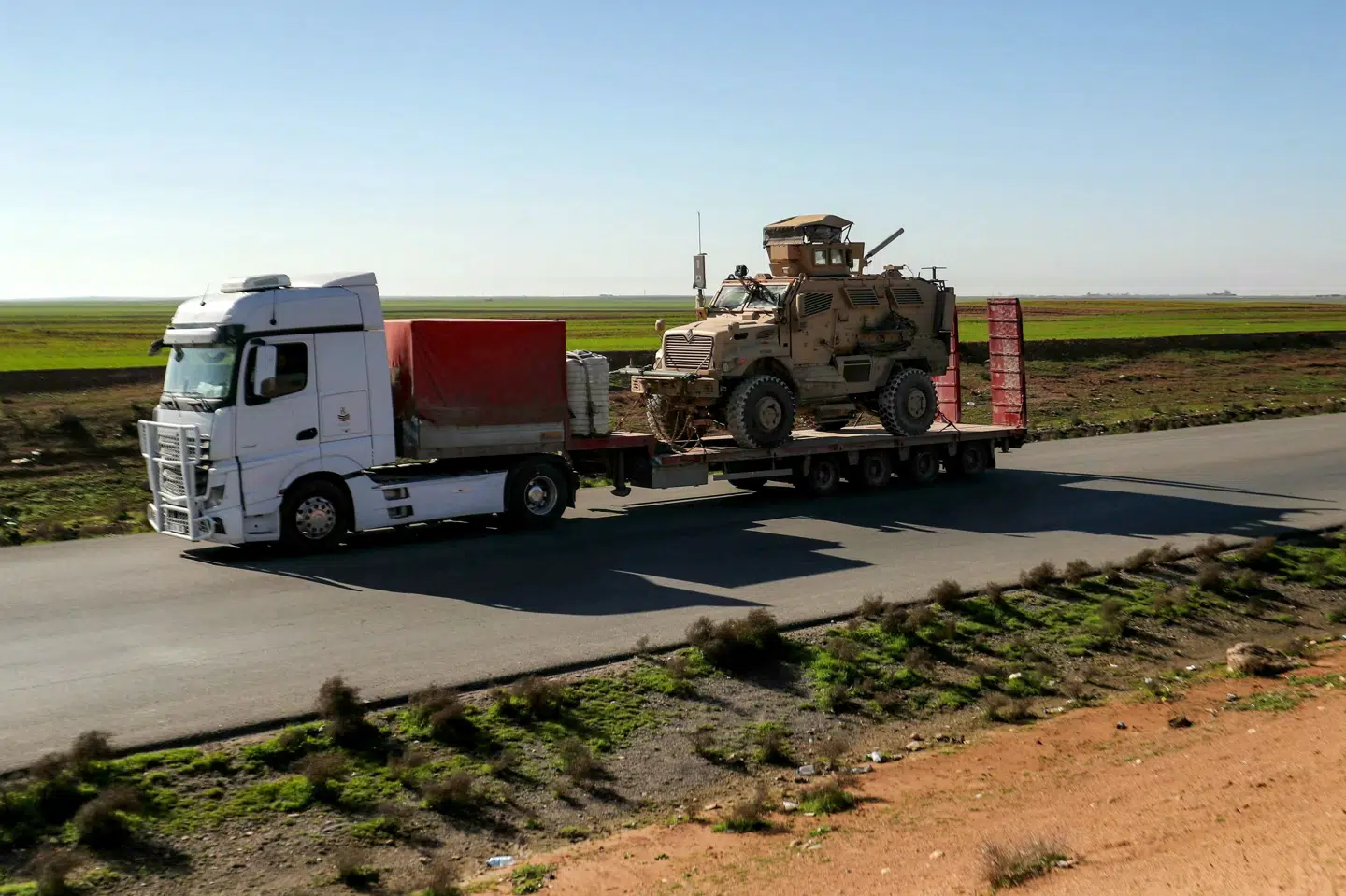 Lastbil med pansret køretøj kører på en motorvej som del af en konvoj i Syrien mandag, hvor USA ifølge kilder trækker sig ud af sin vigtigste base i den nordøstlige del af landet.