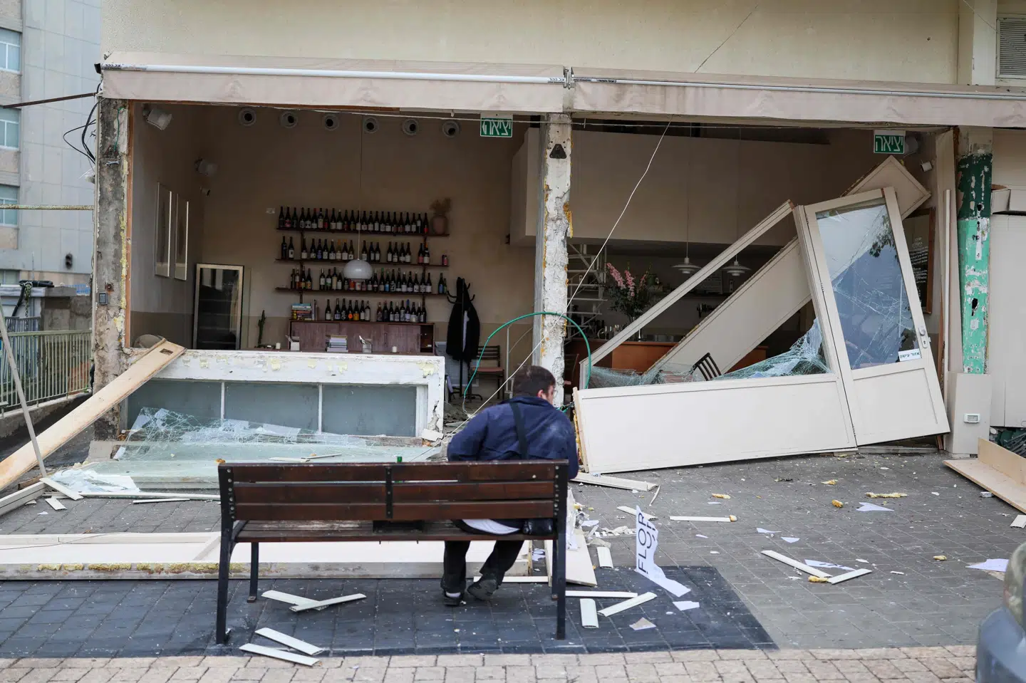 Billede fra lørdag viser en person, der sidder foran beskadiget butik i israelske Tel Aviv efter angreb fra Iran. (Arkivfoto).