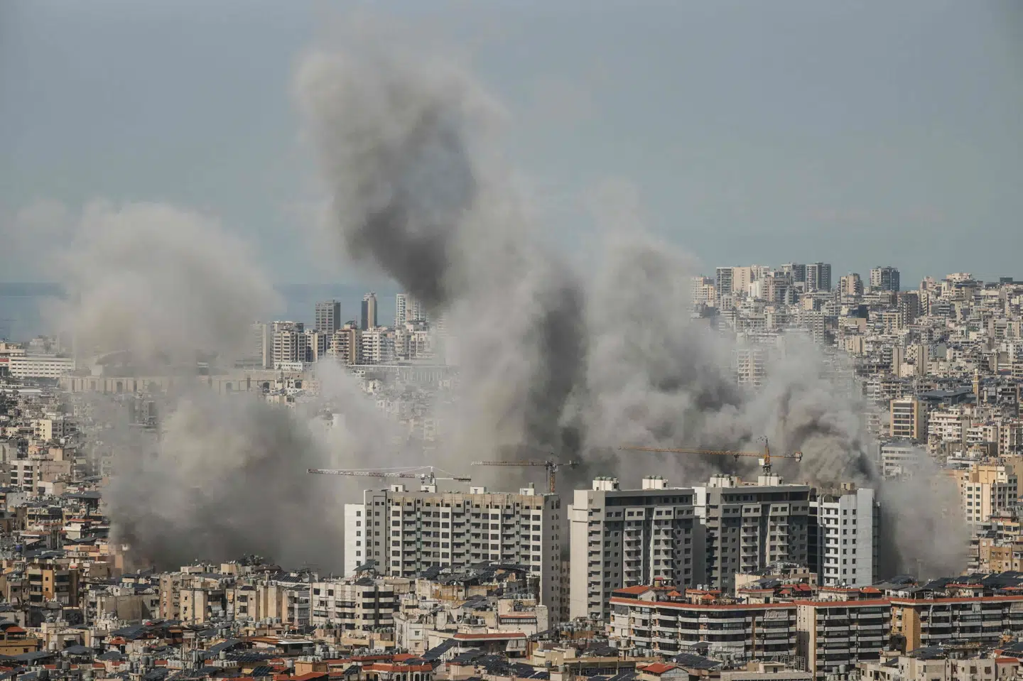 Fredag stiger røg op blandt bygninger i Libanons hovedstad, Beirut, efter israelske angreb. Danskere opfordres til at forlade landet.