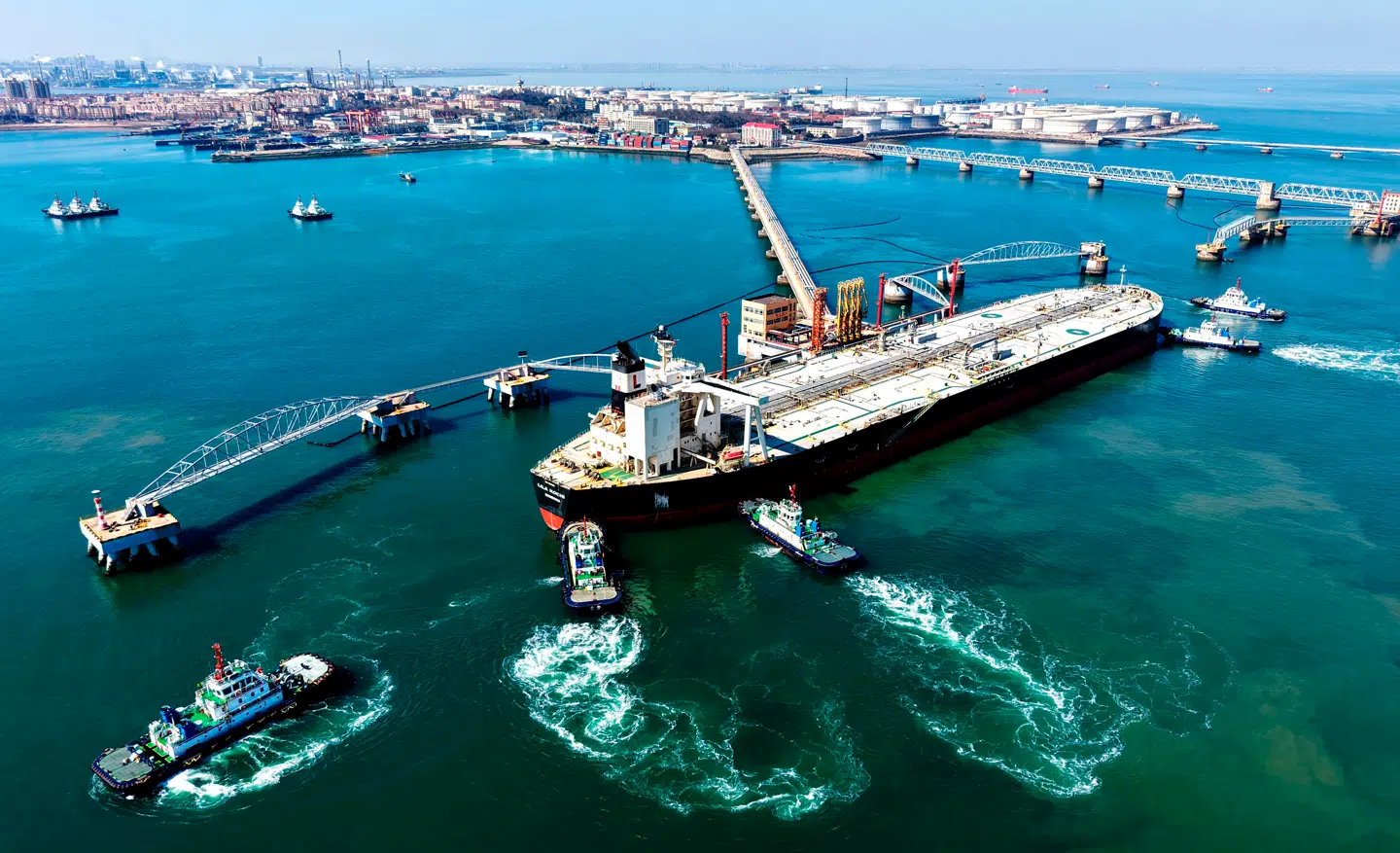 Et olietankskib lodses på plads i havnen i Qingdao i det østlige Kina. Olieprisen skyder mandag morgen i vejret, mens aktiekurserne rasler ned, nu hvor krigen i Mellemøsten er gået ind i sit niende døgn.
