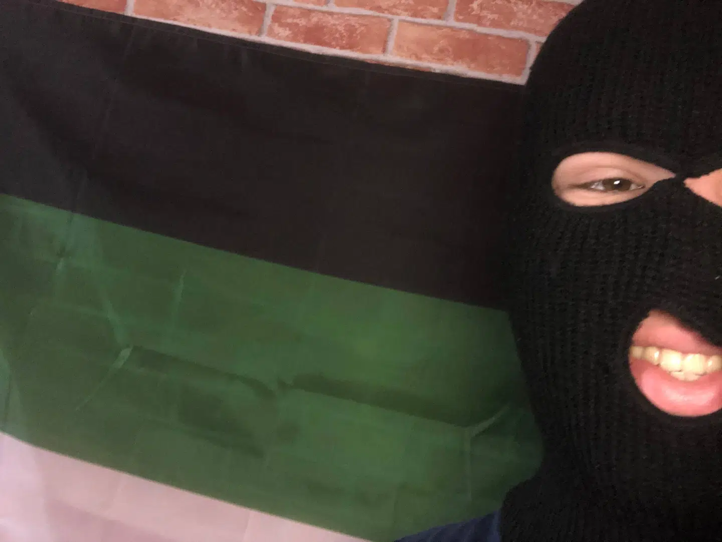 Et billede af en mand foran et flag fra en Telegram-gruppe, der promoverer løsrivelsen af en estisk provins og by, der ligger lige op ad Rusland.