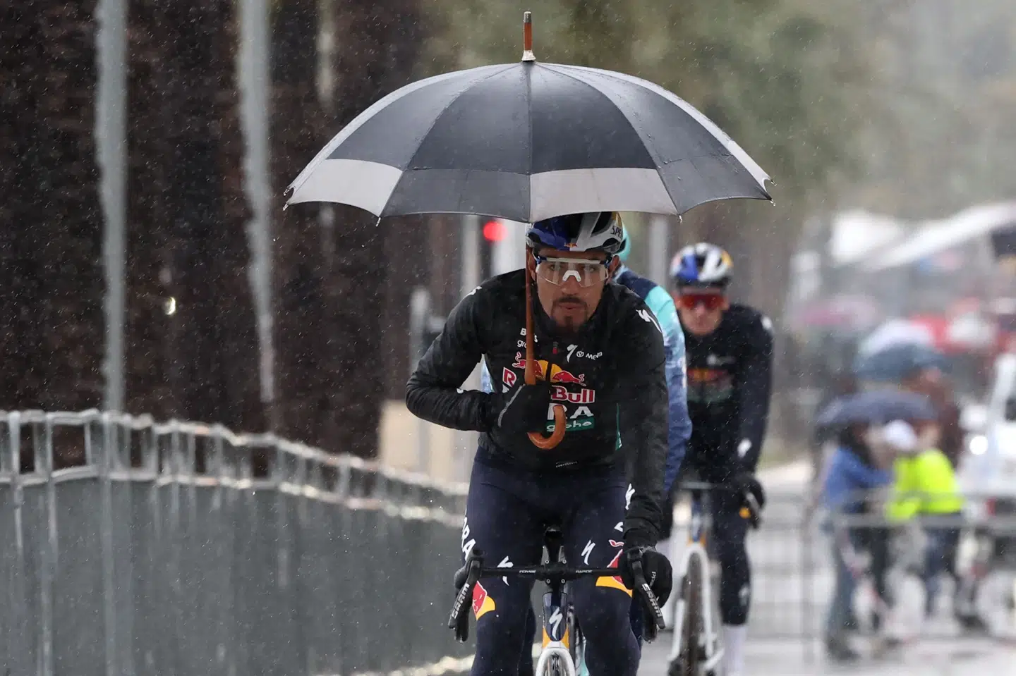 Red Bull-rytteren Daniel Felipe Martínez søger ly for regnen med en paraply under forberedelserne til 7. etape lørdag.