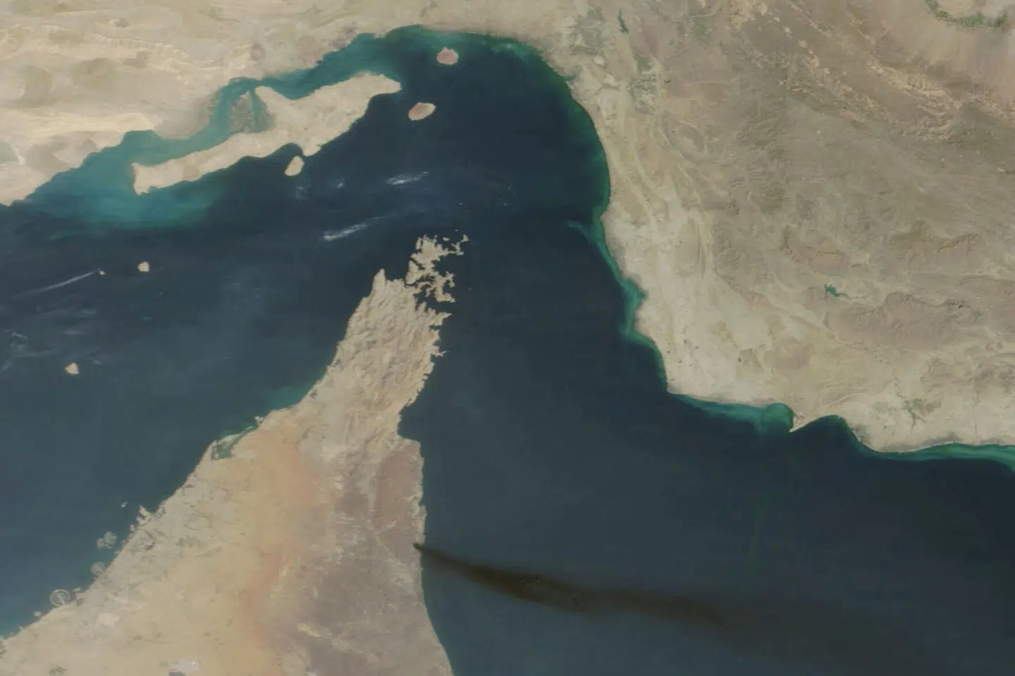 Et satellitbillede viser røg stige op over Fujairah-havnen i De Forenede Arabiske Emirater efter et angreb 15. marts. Fujairah ligger meget tæt på Hormuzstrædet, der er bugten øverst på billedet. (Arkivfoto).