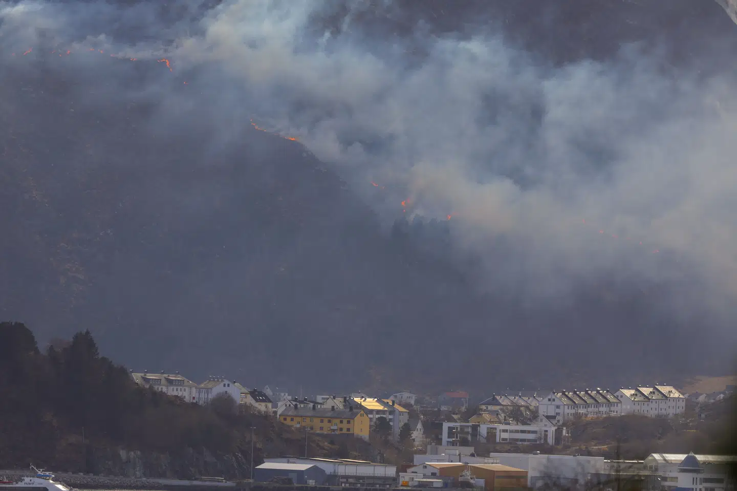 Branden i Ålesund er ikke under kontrol, og der er fare for spredning, skriver NRK. Vinden i fjeldet har ført til, at et stort område brænder.