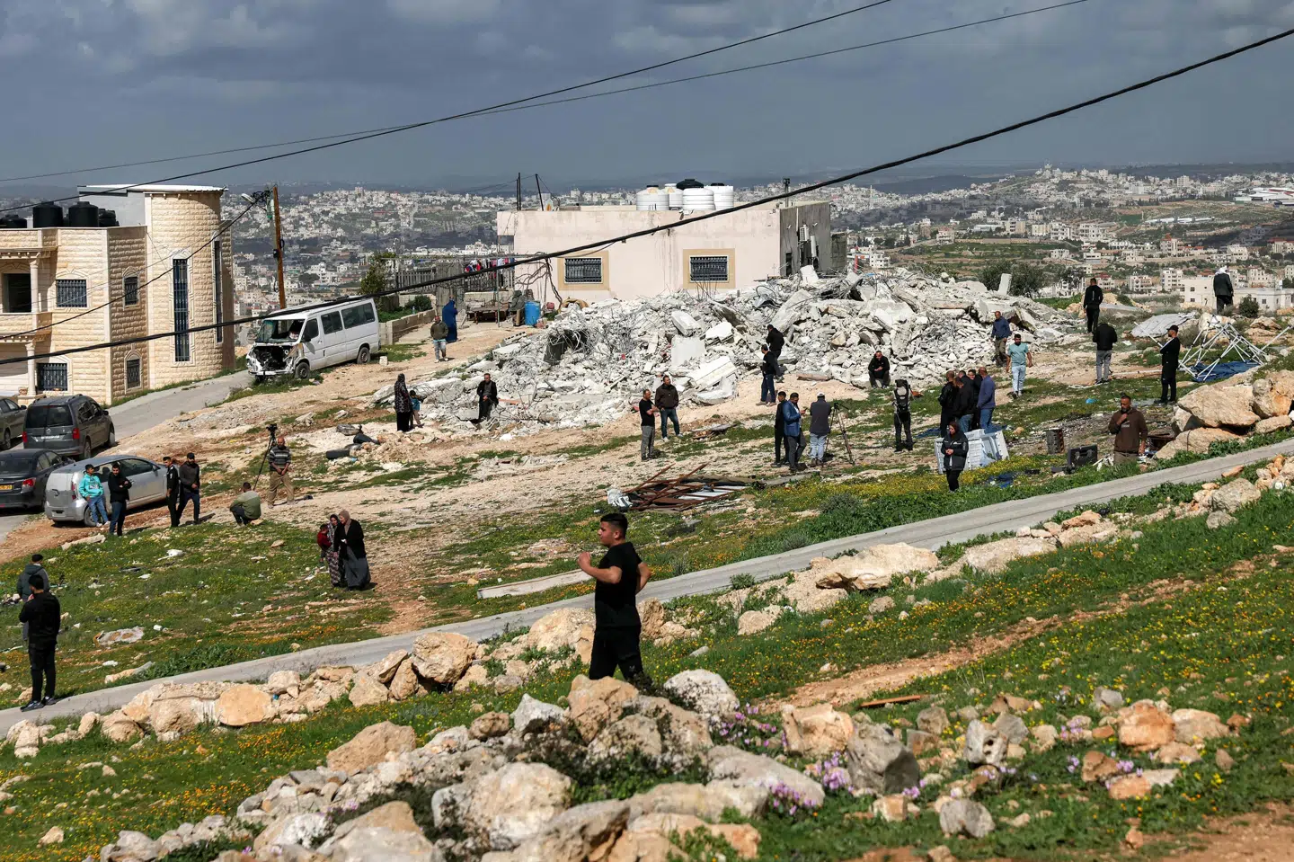 Billedet er fra den 11. februar, hvor lokale palæstinensere ses samle sig, efter at israelske sikkerhedsstyrker havde revet en bygning ned i den mindre by Beit Awwa på Vestbredden. Her meldes fire kvinder onsdag dræbt i angreb fra Iran. (Arkivfoto).