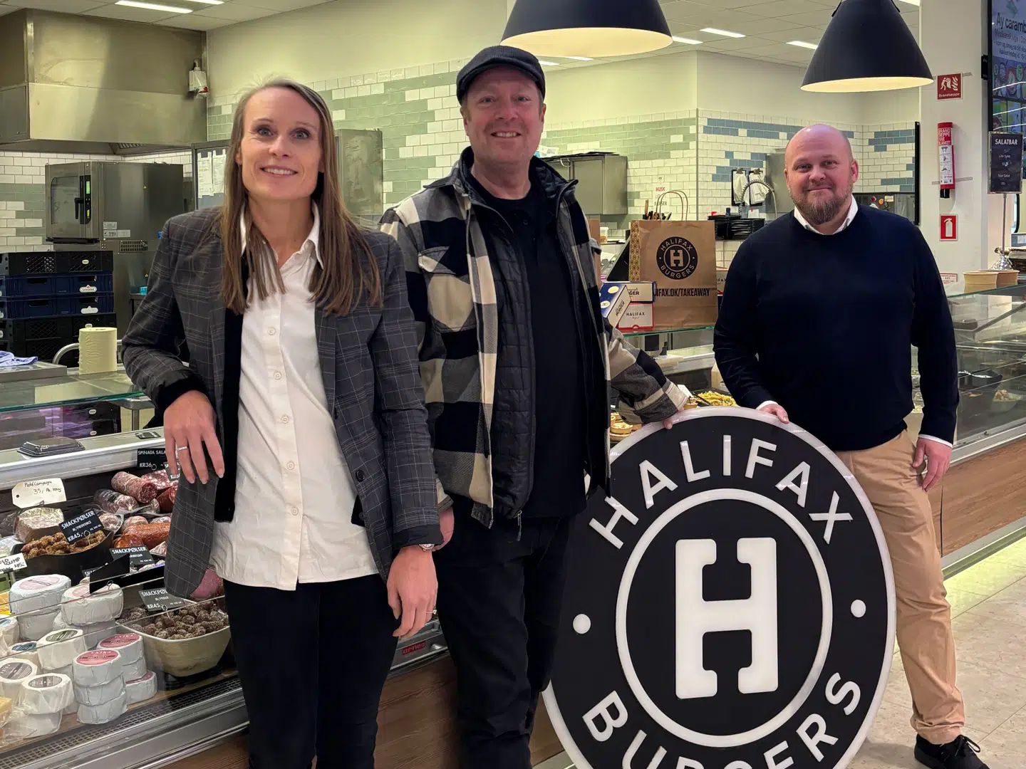Kristine Pilgaard, kommerciel direktør, Peter Bækbro Ahn, stifter af Halifax og Richo Boss, kædedirektør i Meny (t.h.), med et Halifax-skilt i en Meny.
