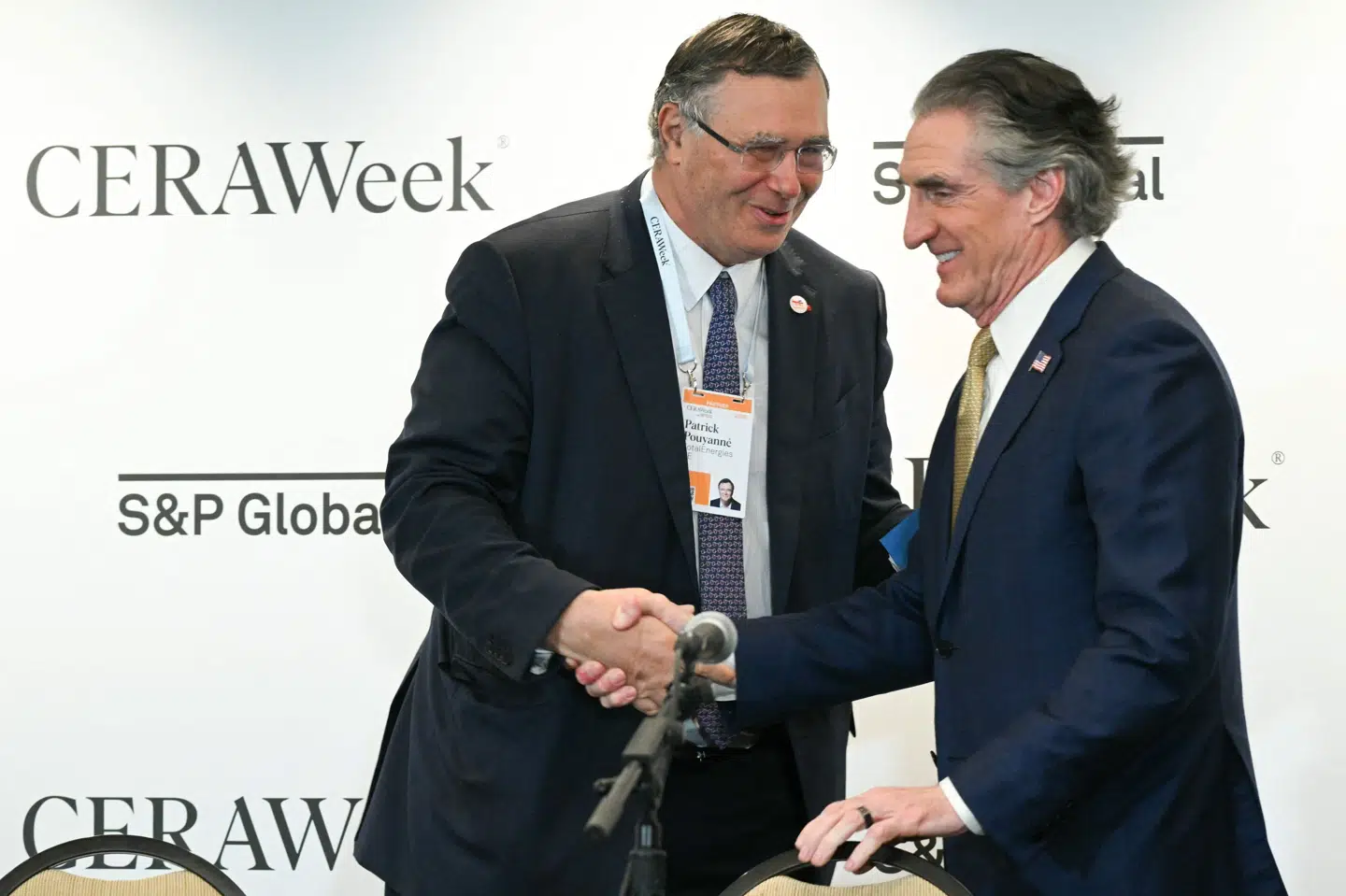 TotalEnergies' topchef, Patrick Pouyanne, og den amerikanske indenrigsminister, Doug Burgum, trykker hånd under konference i Houston.