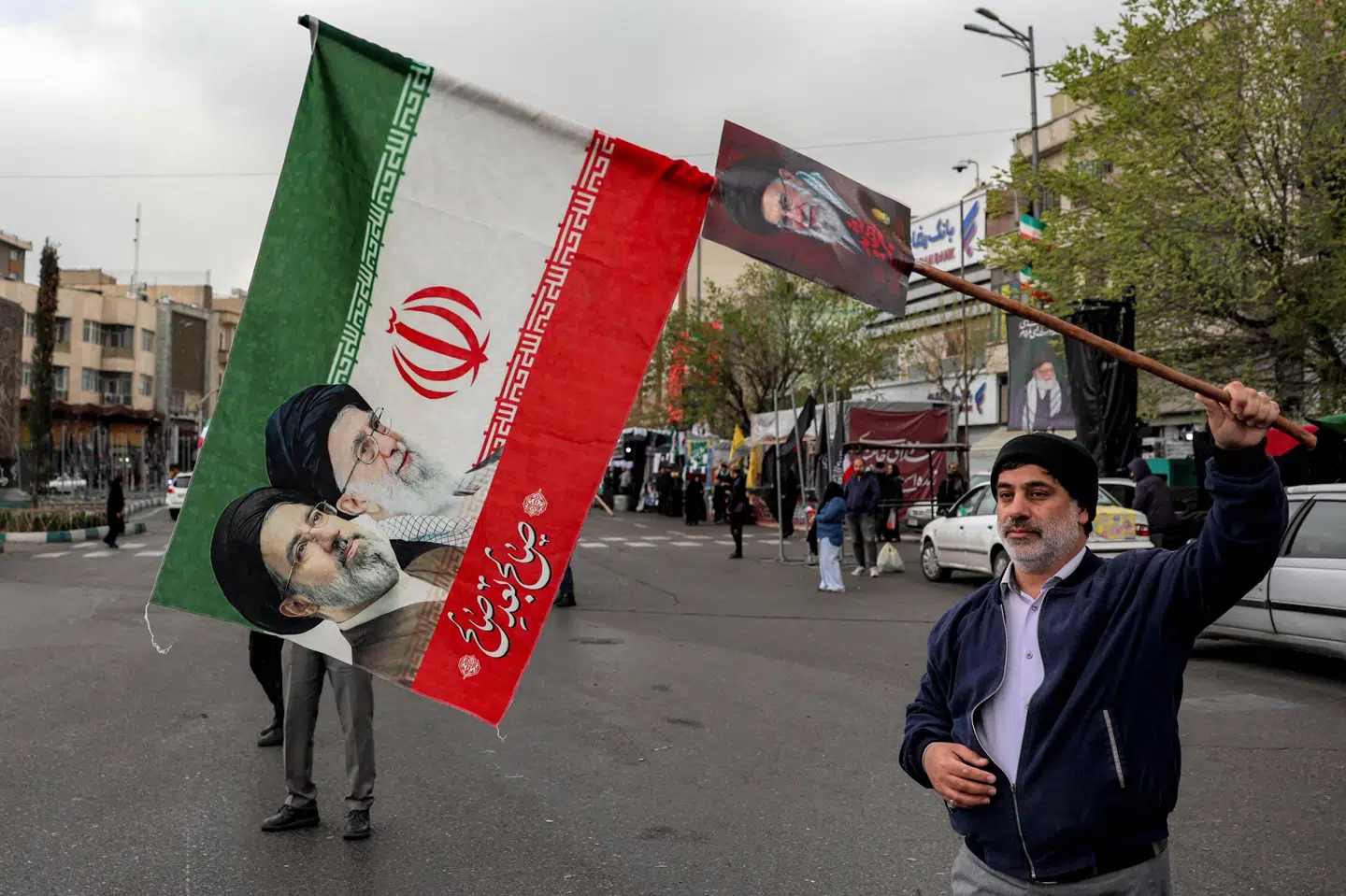 En mand holder i Teheran onsdag et iransk flag op med billeder af både den nye øverste leder i Iran og den forhenværende leder, der blev dræbt.