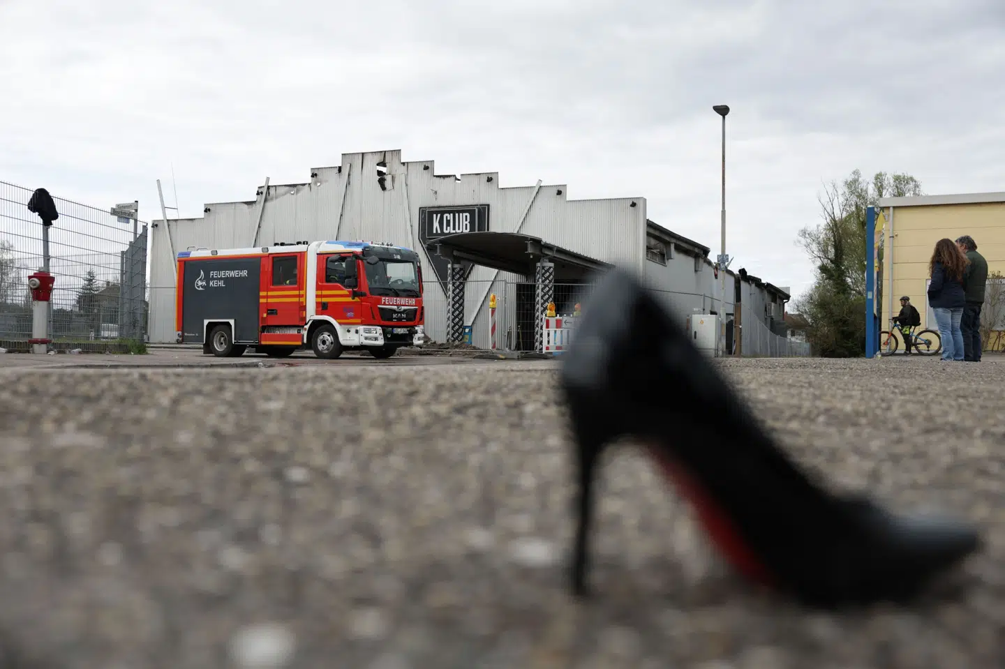 En højhælet sko ses efterladt på jorden, mens brandvæsnet kan ses i baggrunden på billede fra søndag af natklub i tyske Kehl. Her udbrød der natten til søndag en brand.