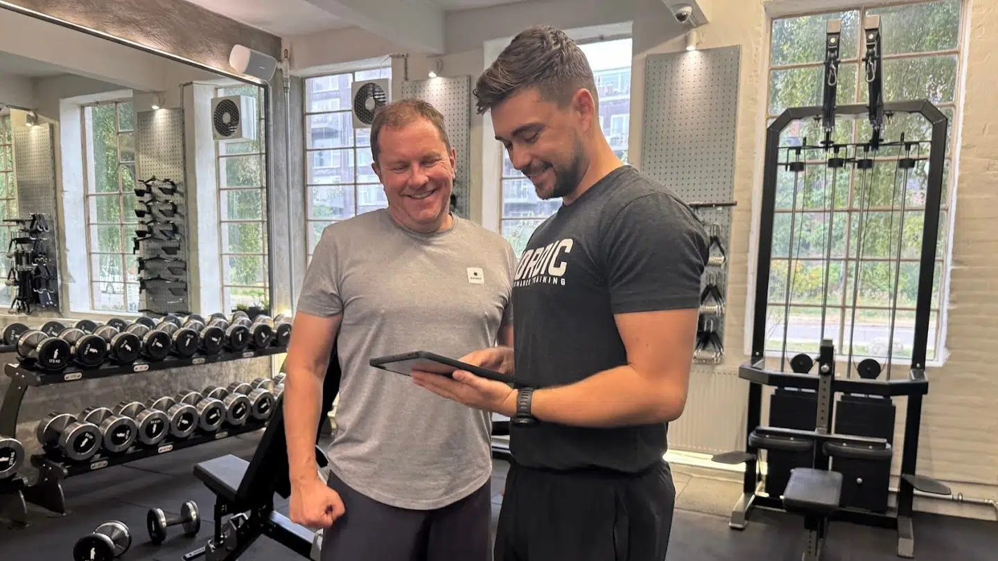 Klient ser sine resultater med sin personlig træner i et privat træningscenter i København.