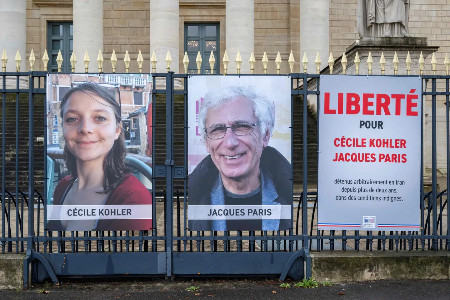 Plakater med fotos af Cécile Kohler og Jacques Paris har været hængt op på hegnet ud for det franske parlament for at minde om deres skæbne i Iran. Nu er de to franskmænd på vej hjem efter at have været tilbageholdt mere end tre år i Iran. (Arkivfoto).