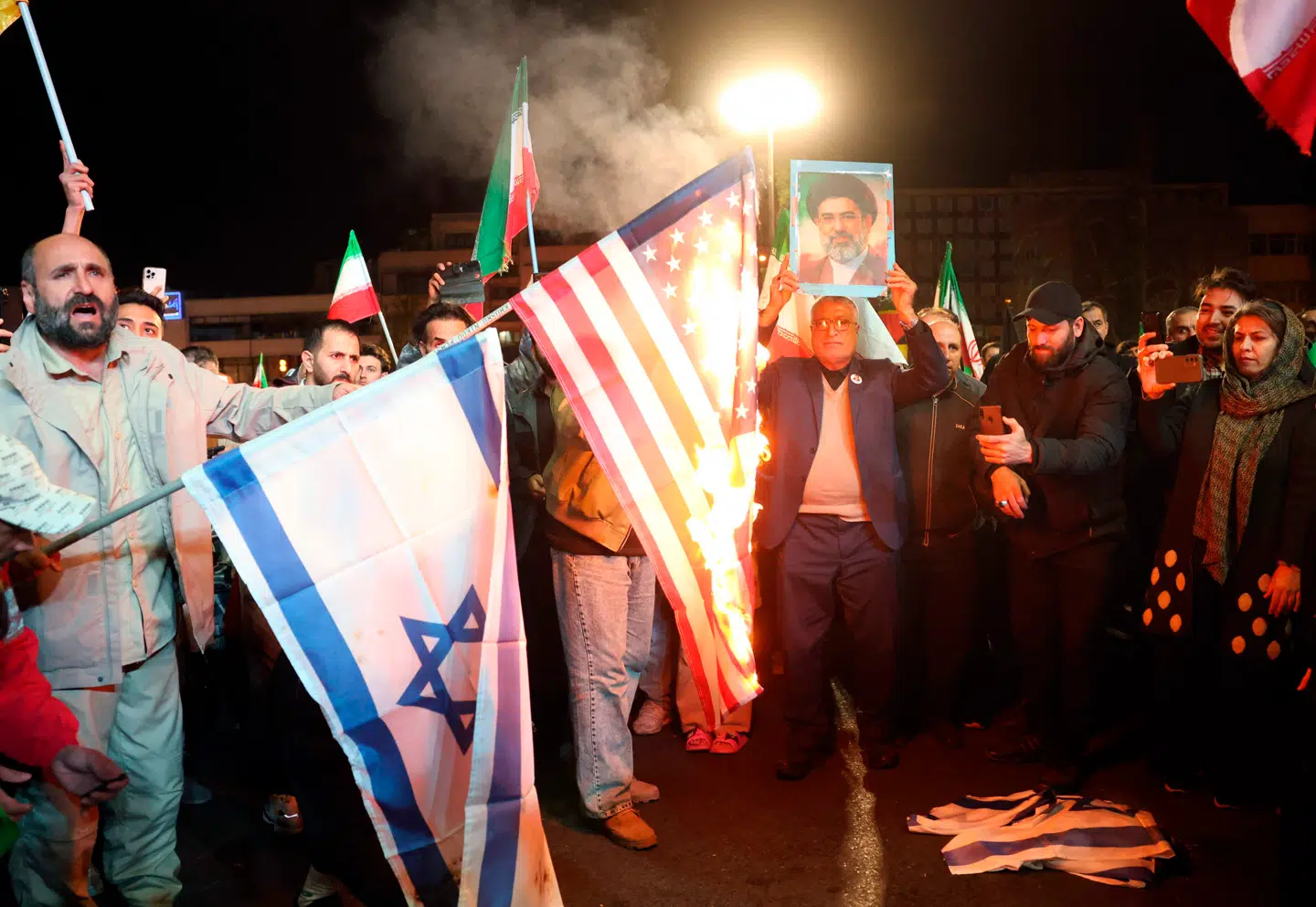 Fest i gaden. Regimetro iranere fejrer nyheden om en våbenhvile ved at brænde amerikanske og israelske flag i Teherans gader. Regimet har god grund til at fejre.
