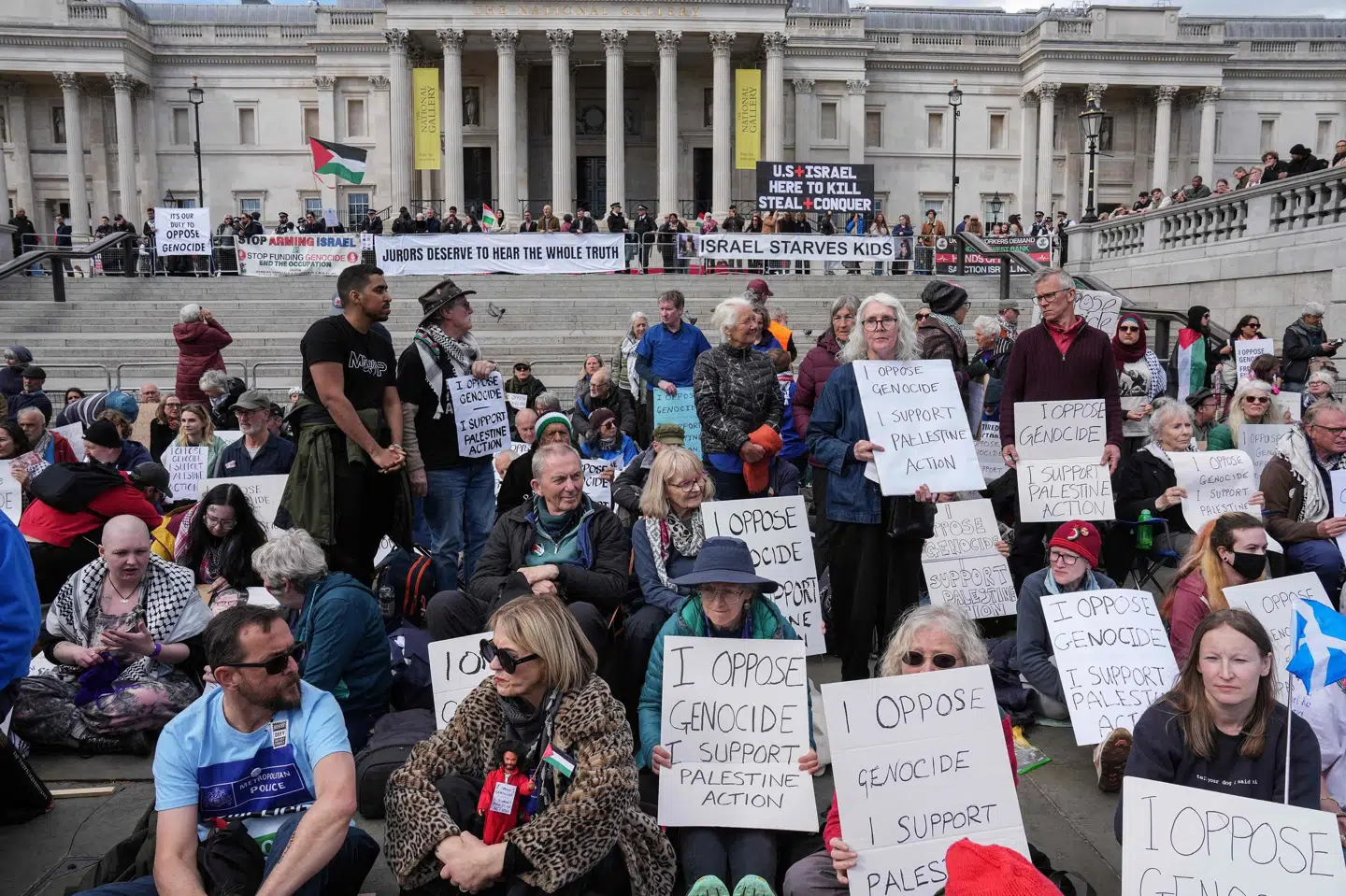 Demonstranter sidder lørdag på Trafalgar Square for at vise støtte til gruppen Palestine Action Group, der blev forbudt sidste år. Senere har en domstol afgjort, at det er et brud på ytringsfriheden, hvilket vil blive anket af den britiske regering.