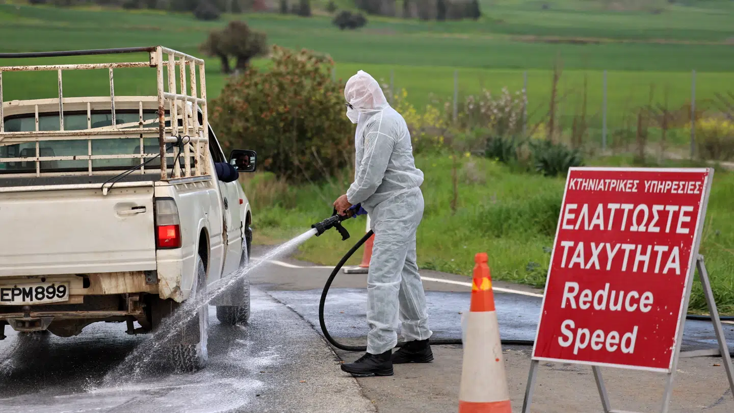 Mand i beskyttelsesdragt spuler biler for sygdom.