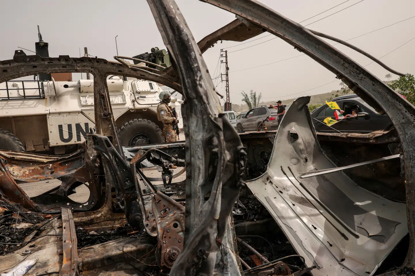 Et medlem af FN's fredsbevarende styrke står ved en udbrændt bil i Qasmiyeh i Libanon. Billedet er fra lørdag.