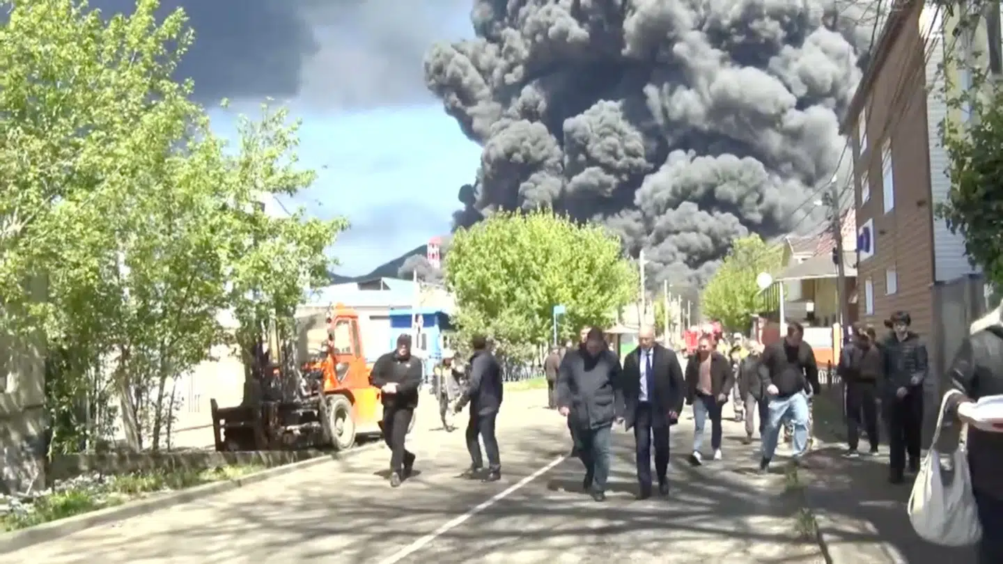 Lokale beboere og embedsmænd i Tuapse, hvor man kan se røgen fra byens olieraffinaderi i baggrunden efter ukrainske angreb.