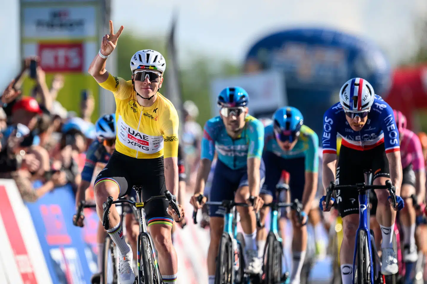 Tadej Pogacar i gult strækker to fingre i vejret, da han krydser målstregen på torsdagens etape i Romandiet Rundt. Det passer med antallet af sejre, han har hentet i løbet af de første tre dage.