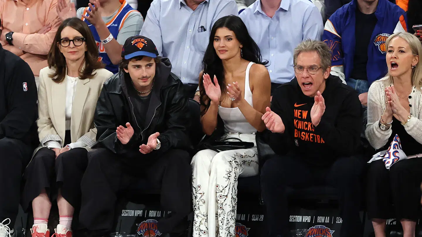 Tina Fey kan ses yderst til venstre i en beige jakke. På hendes venstre side sidder Timothee siddende midt i sin manspreading seance.