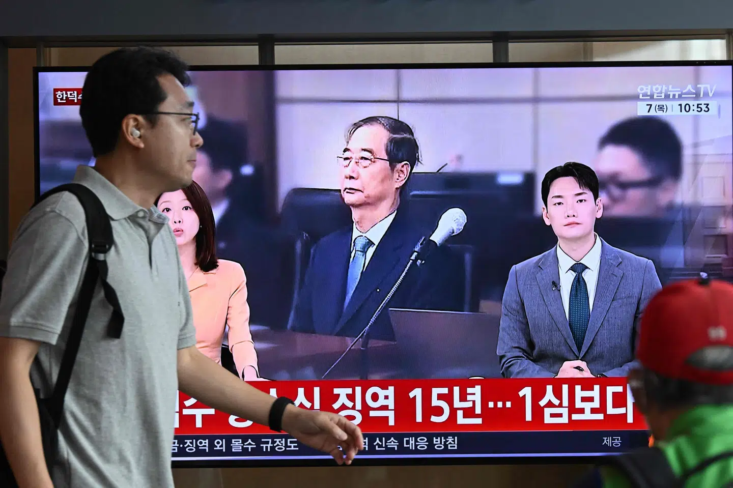 På en togstation i Seoul passerer en mand torsdag et fjernsyn, der viser Han Duck-soo modtage en reduceret straf for sin rolle i en kortvarig undtagelsestilstand i Sydkorea i december 2024.