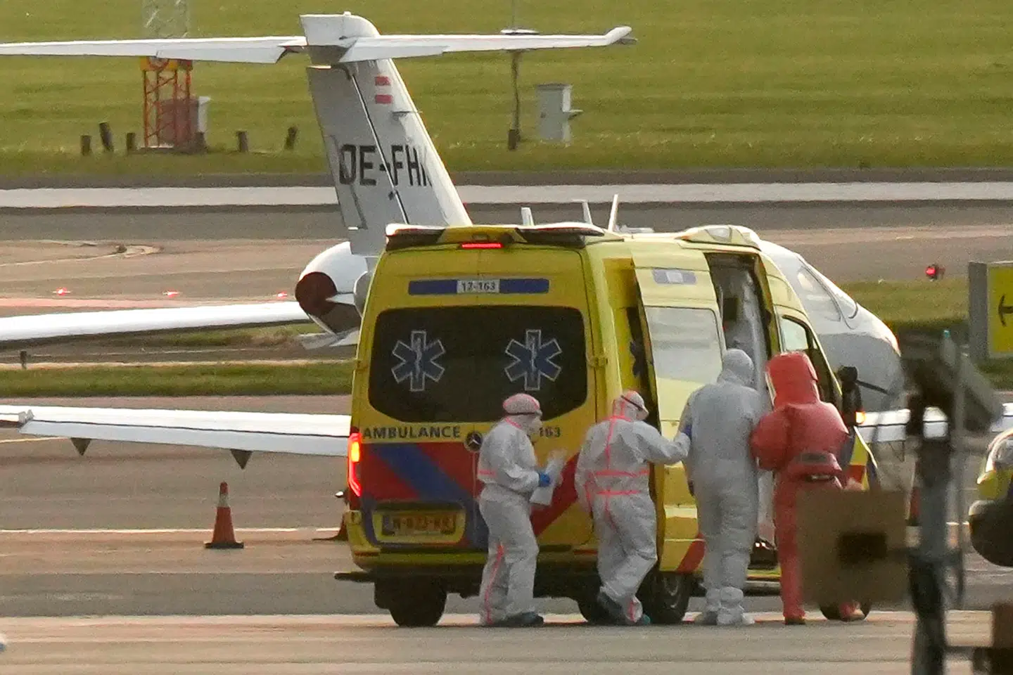 En person i beskyttelsesdragt (2. th.) ledsages ud til en ambulance fra et lægefly, der angivelig transporterer nogle af passagererne fra krydstogtskibet »MV Hondius«, som menes at være smittet med hantavirus, i Schiphol-lufthavnen nær Amsterdam 6. maj 2026.