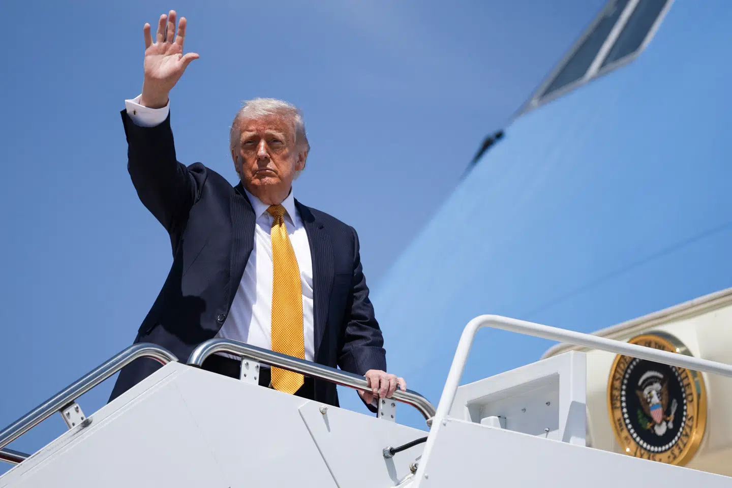 Donald Trump vinker, inden han går om bord på Air Force One og indleder sin rejse mod Kina.
