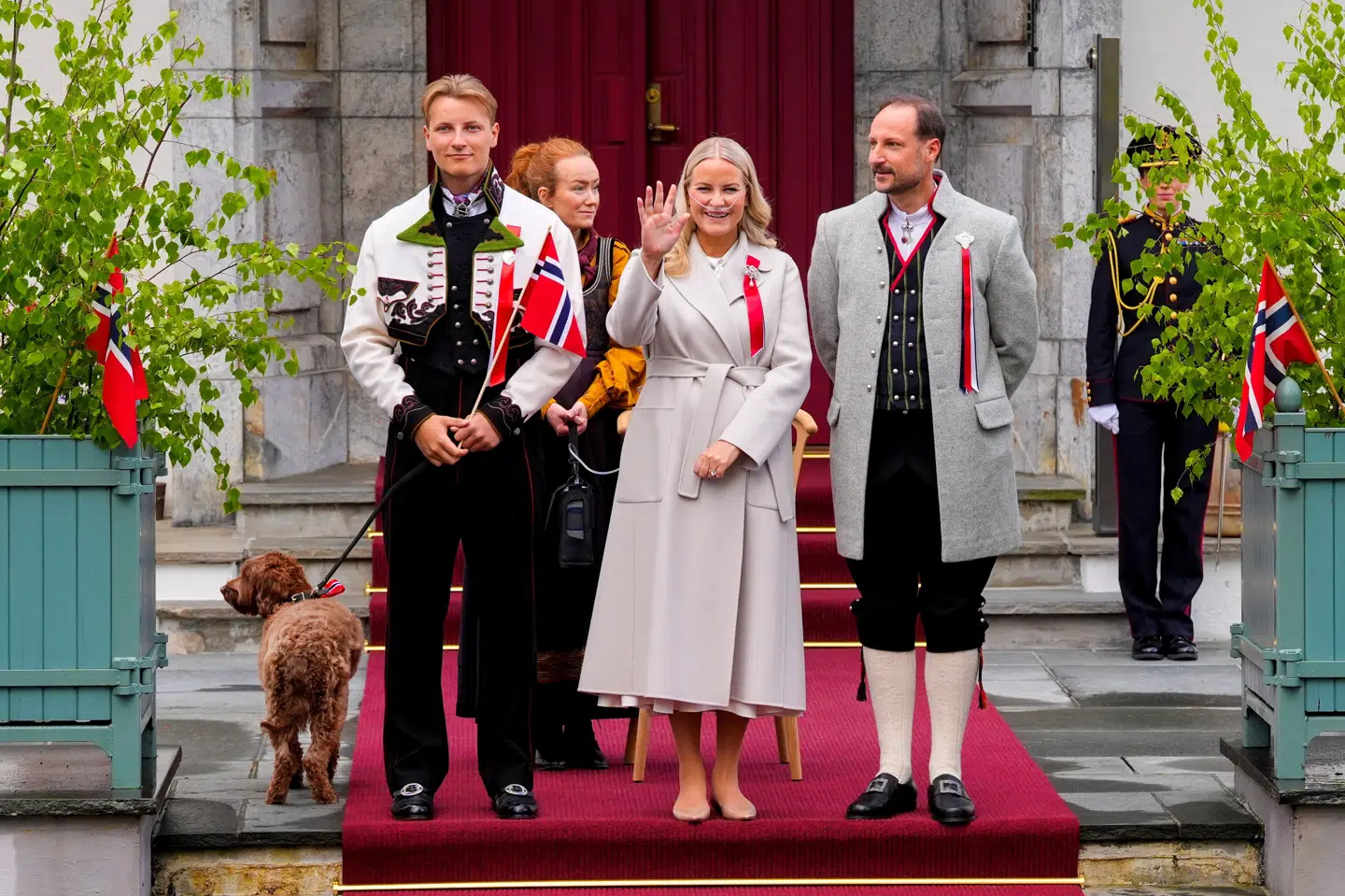Kronprinsesse Mette-Marit, kronprins Haakon og prins Sverre Magnus ser et optog og vinker på Norges nationaldag.