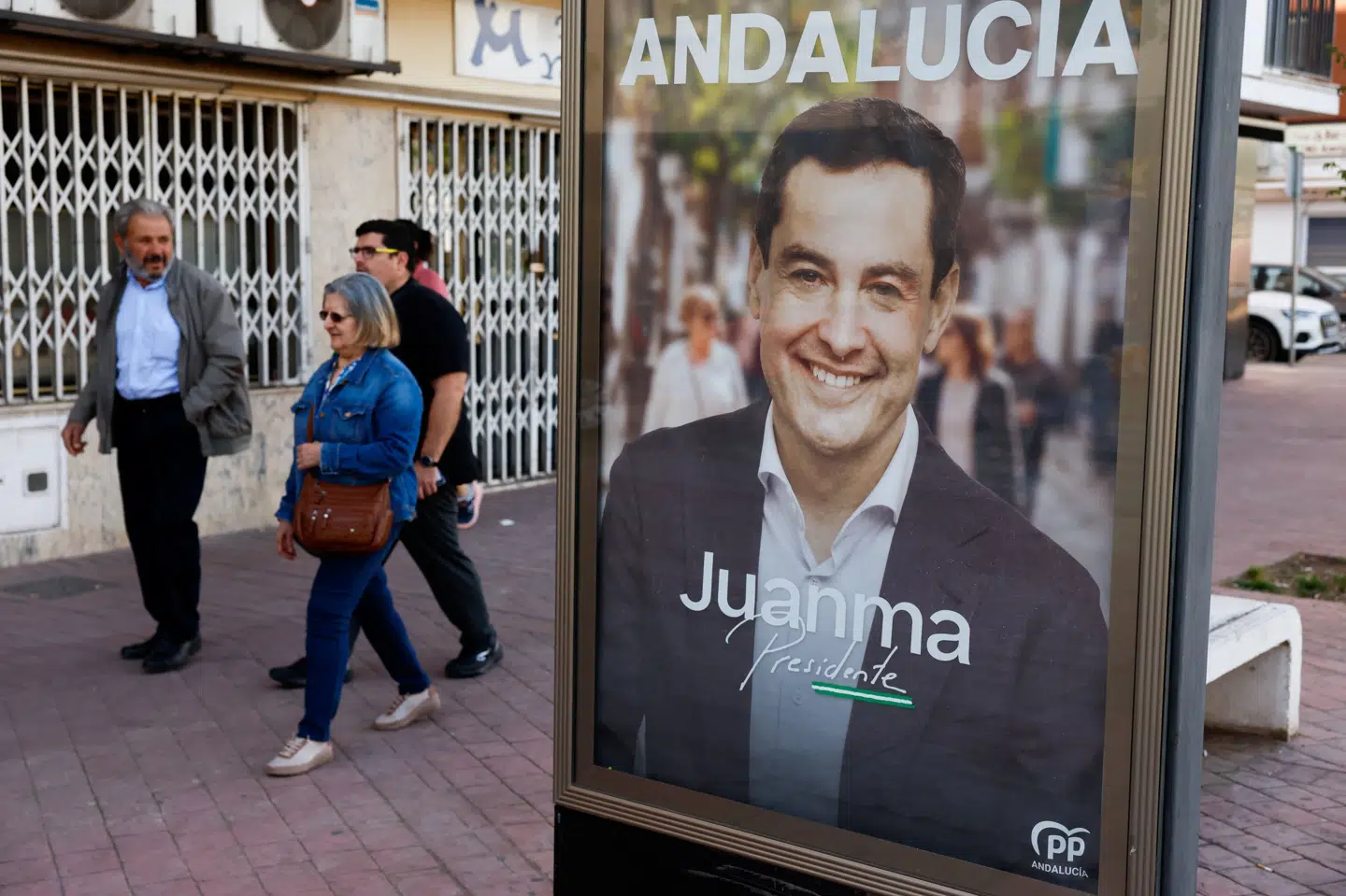Folk går forbi Juanma Moreno Bonilla - den regionale politiske leder og kandidat for det konservative parti, PP - søndag under valg i den sydspanske region Andalusien. (Arkivfoto).