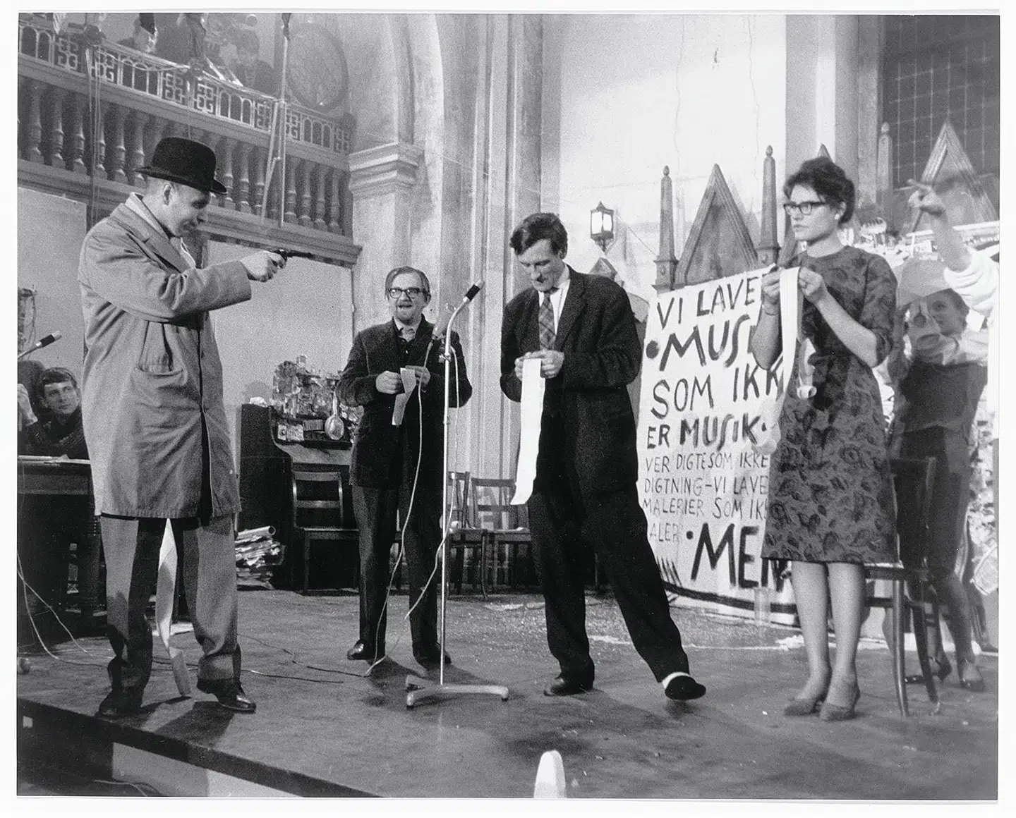Her opfører George Maciunas, Albert Mertz, Arthur Köpcke og Alison Knowles værket »In Memoriam Adriano Olivetti, Version 1 Poem« i Nikolaj Kirke, november 1962