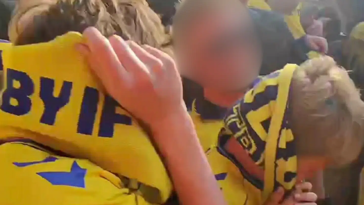 Her ses to Brøndby-fans – herunder et barn – forsøge at beskytte sig mod gløderne med deres halstørklæder.