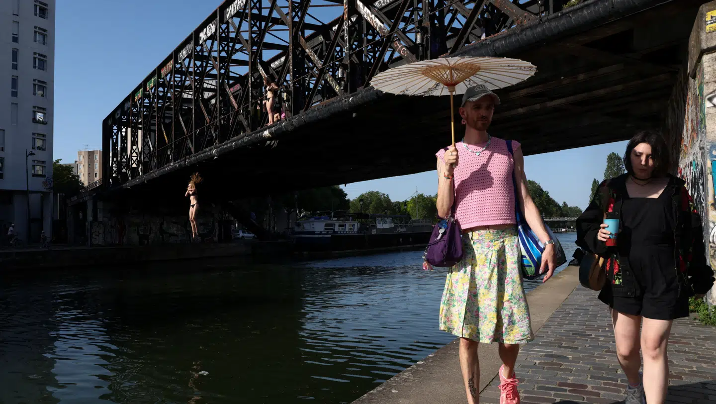 Folk går langs Canal de l'Ourcq i Paris, mens en person springer i vandet i 35 graders varme.