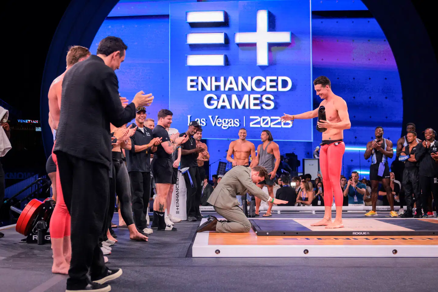 Administrerende direktør og medstifter af Enhanced Games, Maximilian Martin, knæler foran den græske svømmer Kristian Gkolomeev, som netop har slået verdensrekorden i mændenes 50 meter fri.