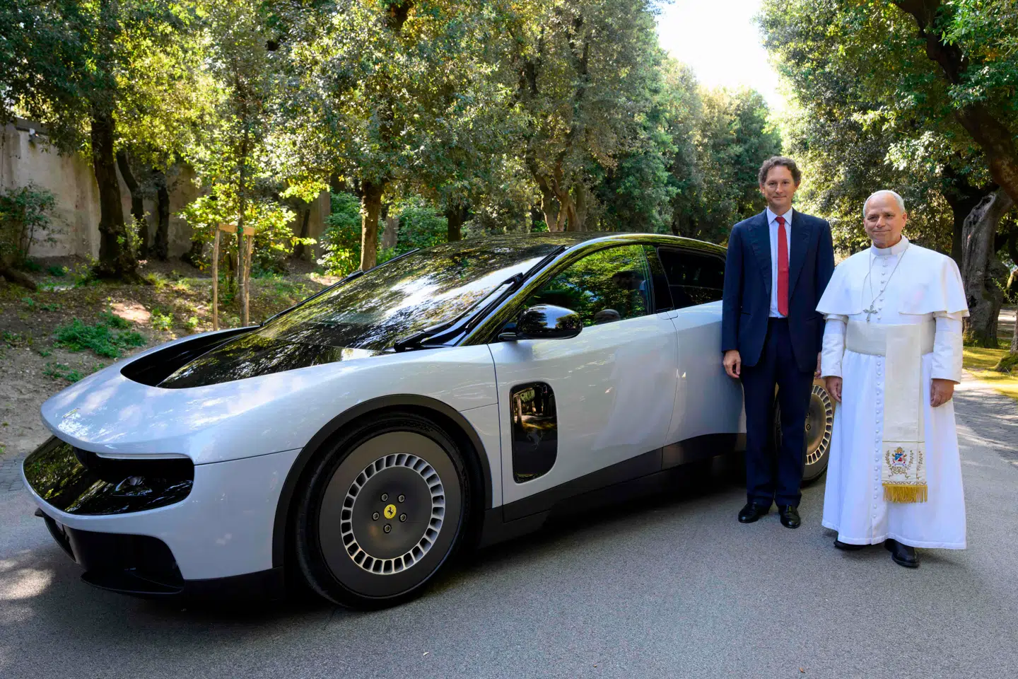 Der er en helt særlig årsag til folks reaktioner på den nye Ferrari Luce. For det handler ikke bare om bilen, men en indskrænket frihed, lyder det i denne kommentar. Her ses Ferraris formand John Elkann og pave Leo XIV posere ved siden af den nye model. Foto: Handout/AFP/Ritzau Scanpix