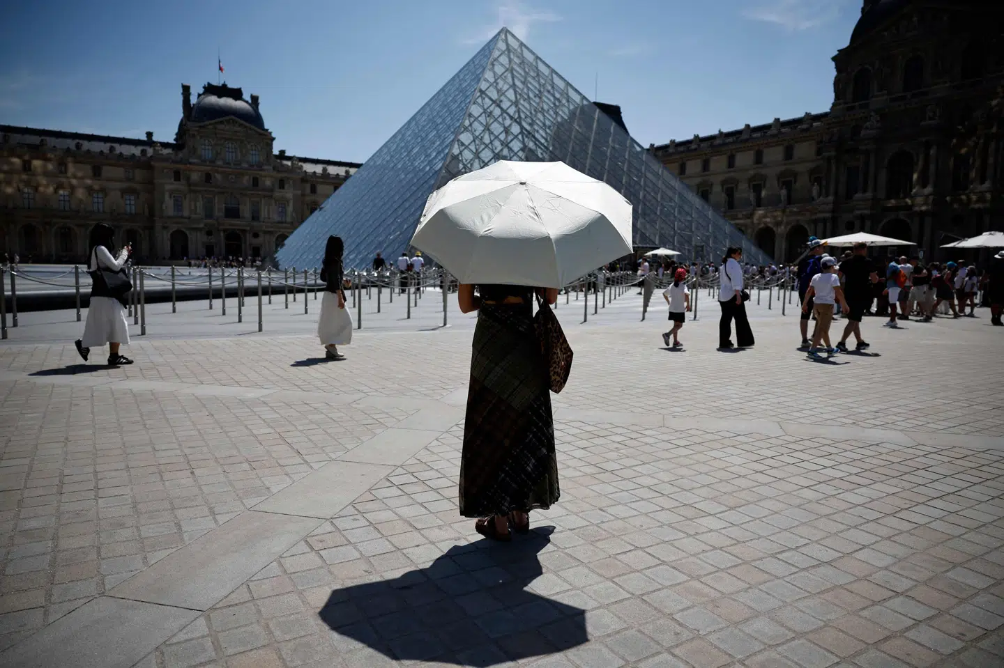 En person beskytter sig mod solen foran det verdensberømte kunstmuseum Louvre i Paris under hedebølge sent i maj i Frankrig. (Arkivfoto).