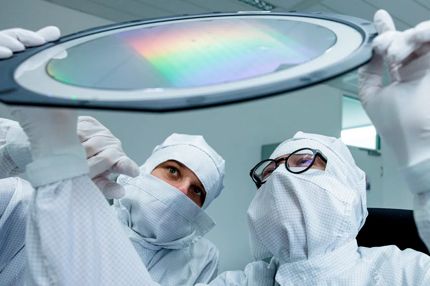 To medarbejdere i Infineon kigger på en mikrochip på et laboratorie i Dresden.