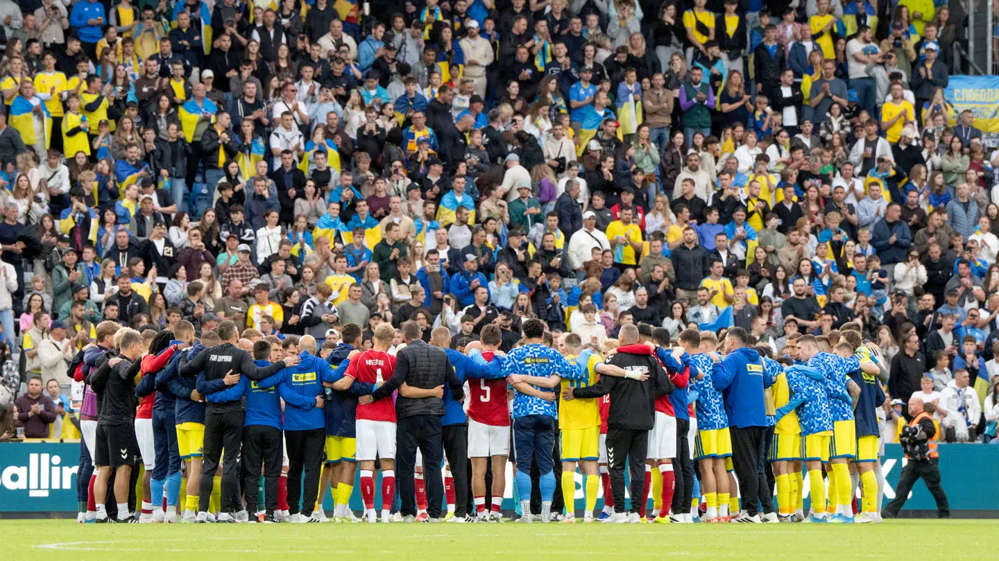 Både danske og ukrainske spillere samles, efter Christian Eriksen var blevet kørt væk i en ambulance.