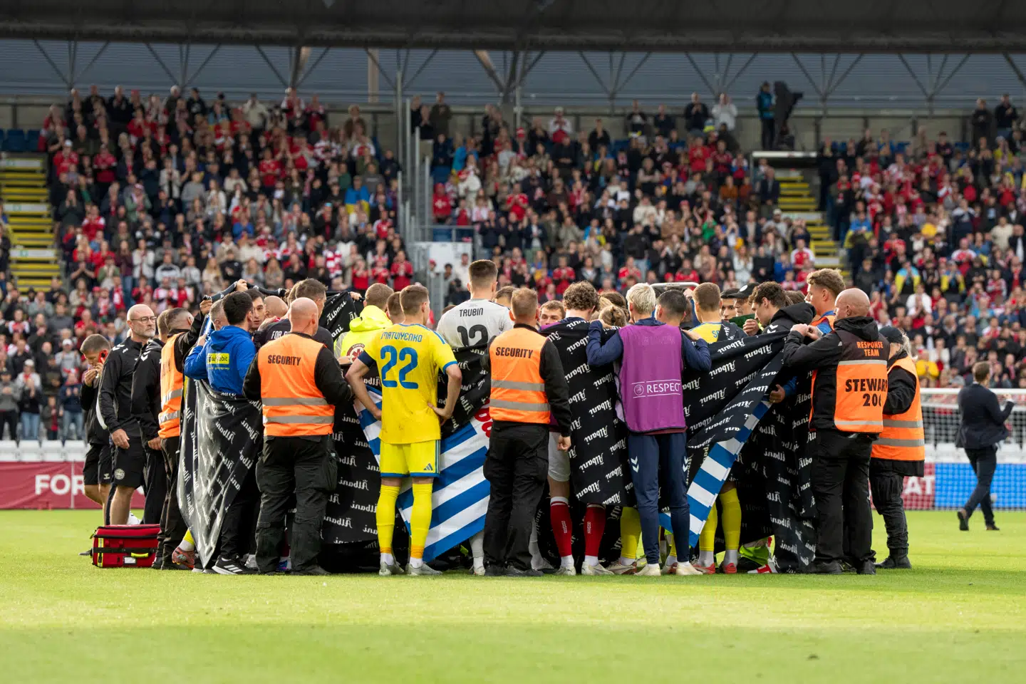 Både danske og ukrainske spillere slå søndag ring om Christian Eriksen, efter han faldt om under fodboldlandskampen mellem Danmark og Ukraine på Odense Stadion.