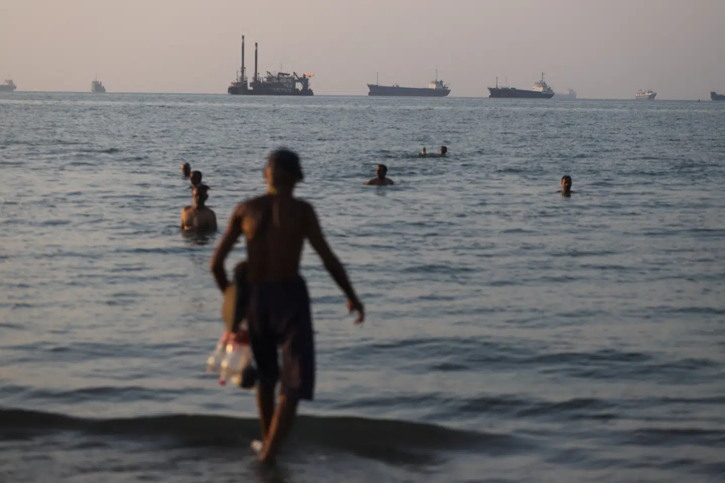 Skibe i Hormuzstrædet og mennesker på stranden ved Bandar Abbas i Iran 8. juni.