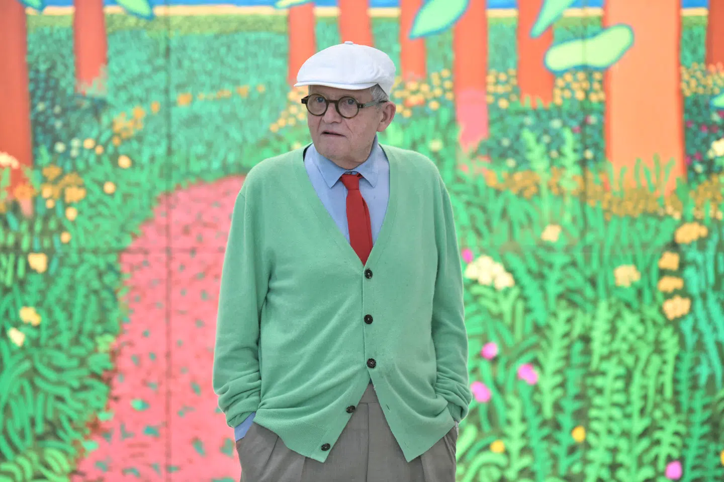 Den britiske billedkunstner David Hockneys karriere strakte sig over mere end 60 år. Her ses han i 2017 foran sit maleri »The Arrival of Spring in Woldgate, East Yorksire in 2011«.