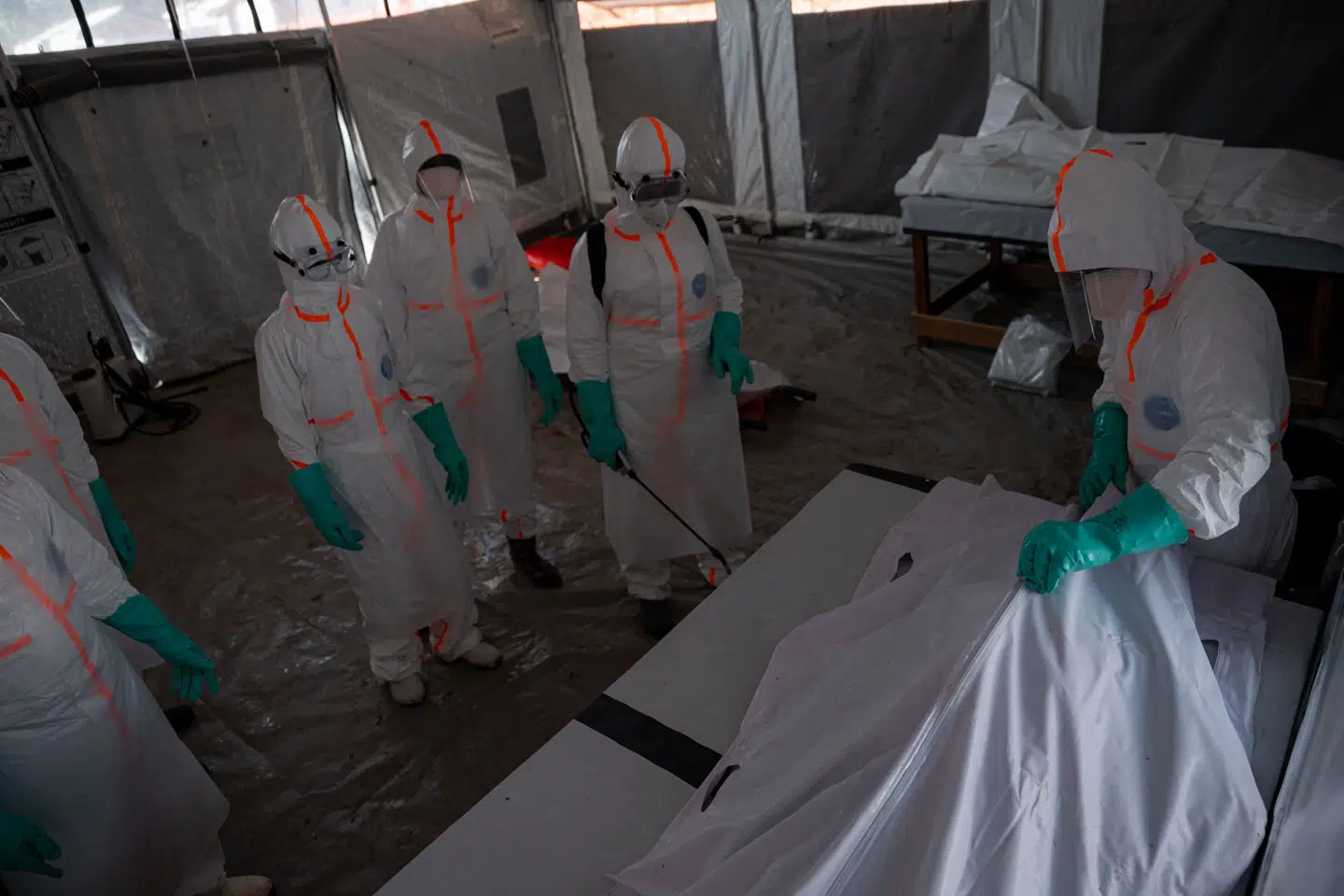 Læger bærer beskyttelsesdragter, da de lørdag tilser en person, der er død som følge af smitte med ebola.