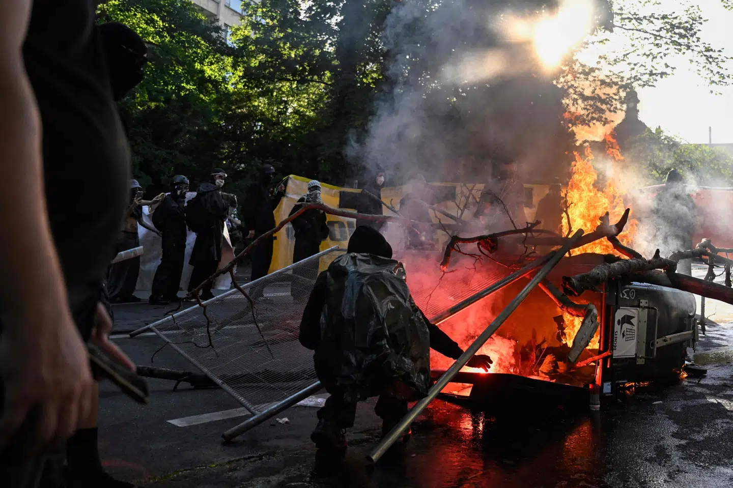 En demonstrant står ved en brændende skraldespand i Genève under demonstration mod G7-møde søndag. Topmødet skal finde sted i den nærliggende by Evian.