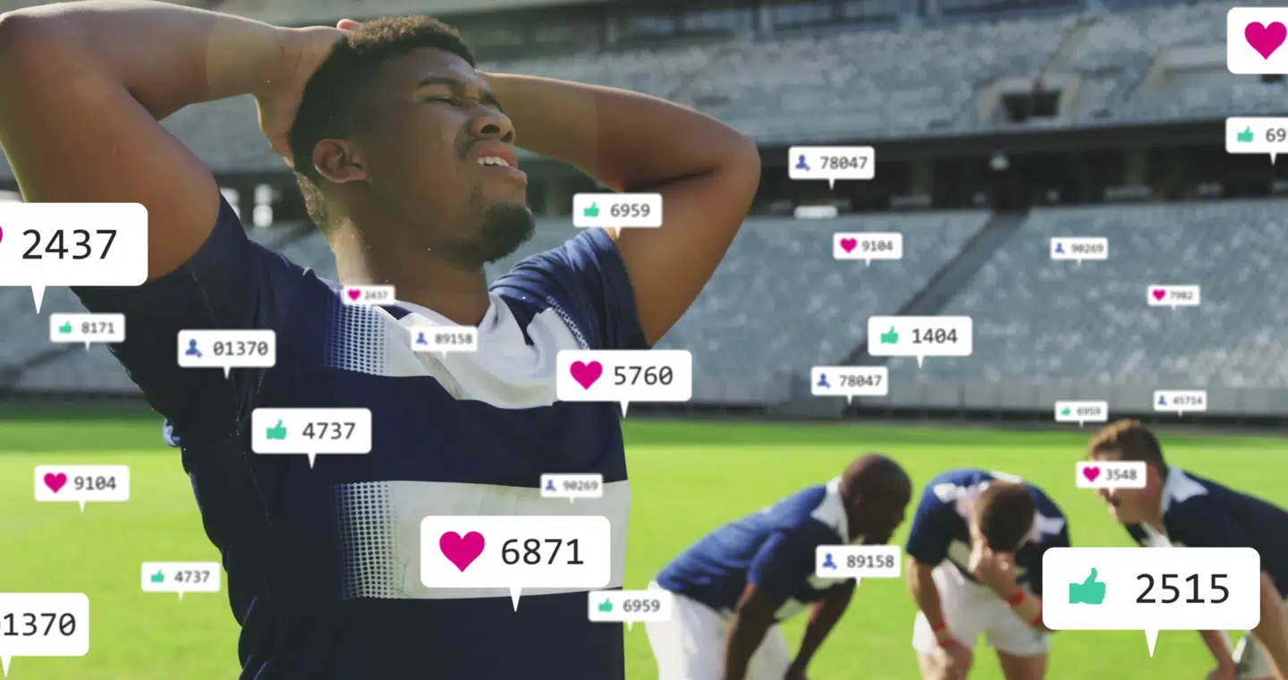 Gripping head soccer player in navy jersey on pitch at stadium, with floating social media icons. Athletes, teamwork, stadium, landscape, endurance, competition, motivation