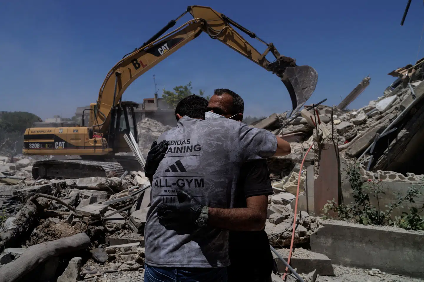 Redningsfolk omfavner hinanden i byen Barish i det sydlige Libanon lørdag efter et israelsk luftangreb. Iran siger lørdag, at Hormuzstrædet nu er blevet lukket igen på grund af Israels angreb i Libanon.