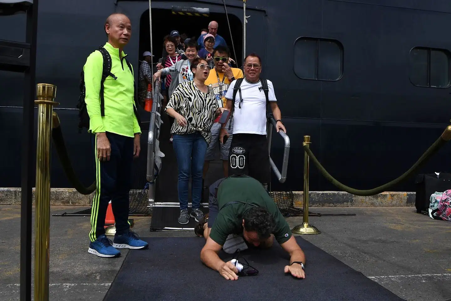 En passager kaster sig til jorden, da passagererne endelig får fast grund under fødderne i Cambodia. (Photo by TANG CHHIN Sothy / AFP)