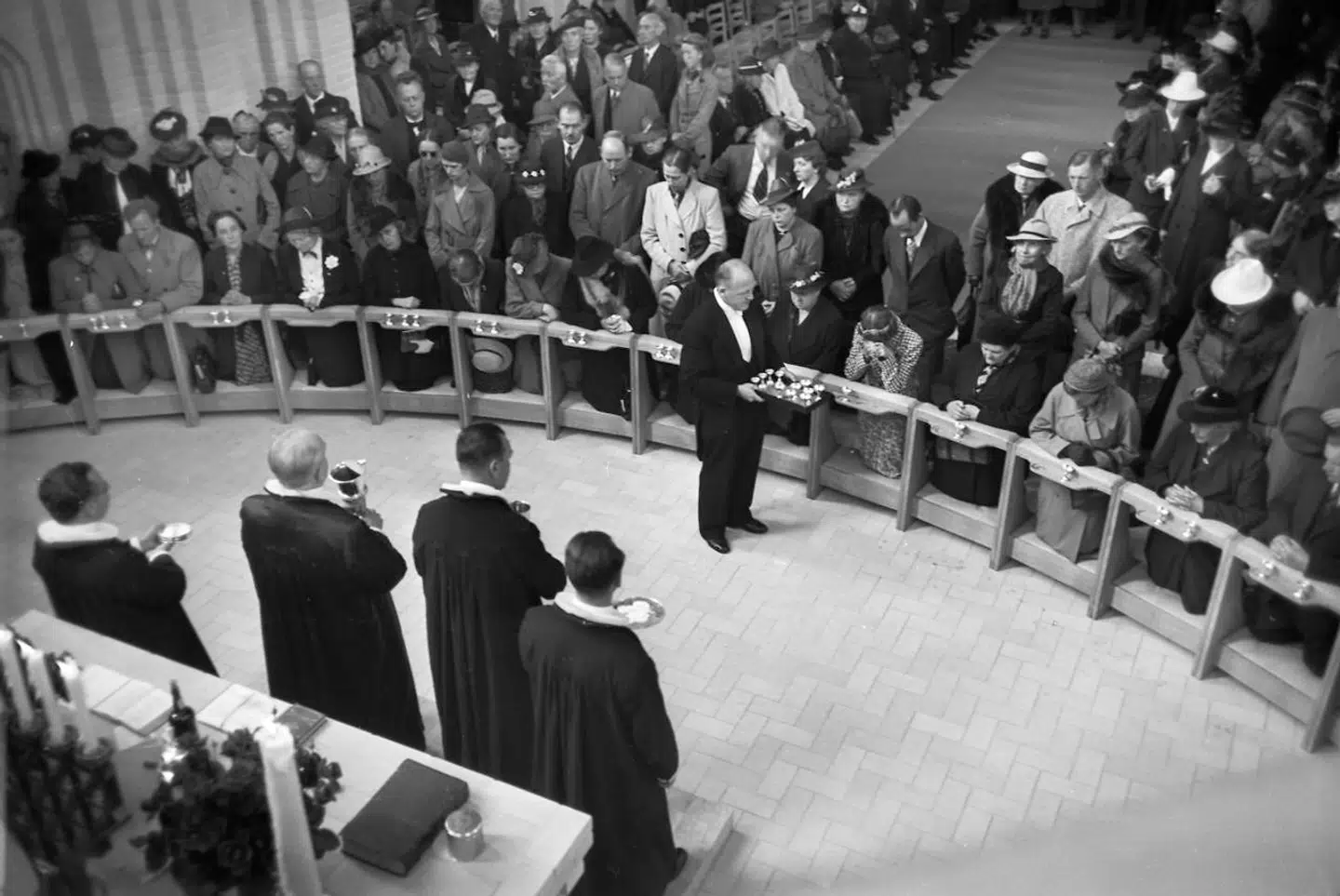 »Tingene må ikke blive så hellige, at man ikke kan reagere, hvis der står liv på spil,« siger præst Poul Joachim Stender om sin aflysning af nadveren i Kirke Saaby Kirke. Arkivbillede forestiller altergang og nadver ved indvielsen af Grundtvigskirken på Bispebjerg i 1940. Fotografen er ukendt.