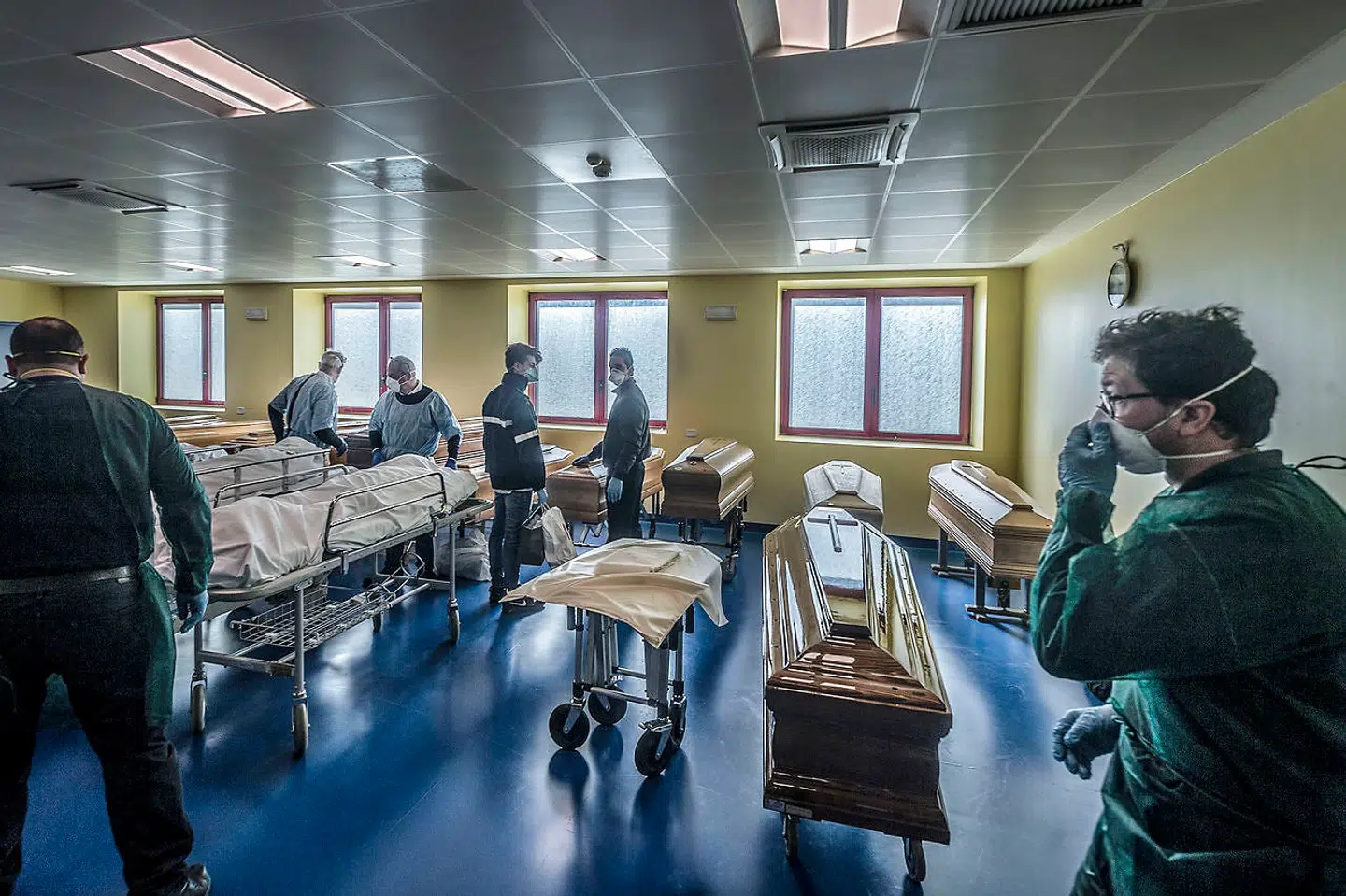 I lighuset på Ponte San Pietro-hospitalet i Bergamo bliver lig fragtet fra sygesengen og ned i kisten.