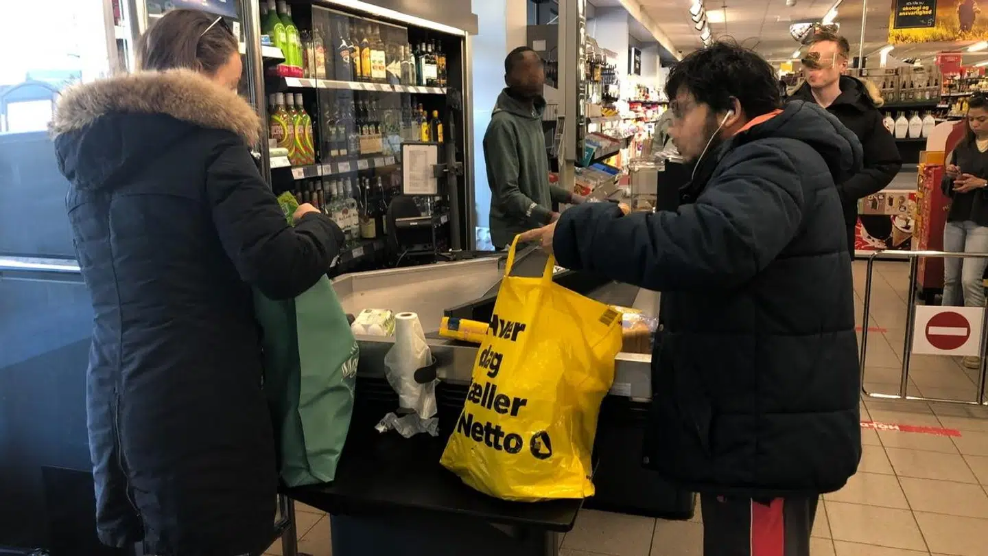 To personer i Netto står, og pakker deres varer ned.