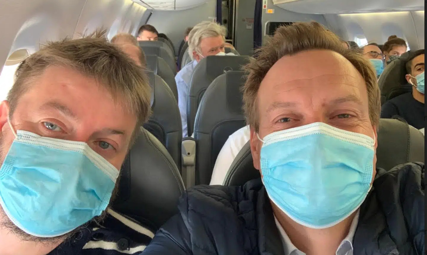 Rasmus Tantholdt sammen med sin kollega i et fyldt fly.