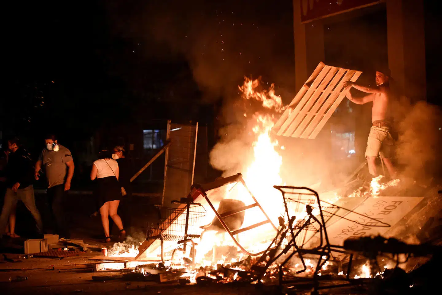 En demonstrant smider brænde på bålet nær politiets hovedkvarter i Minneapolis, hvor de fire politibetjente var ansat.