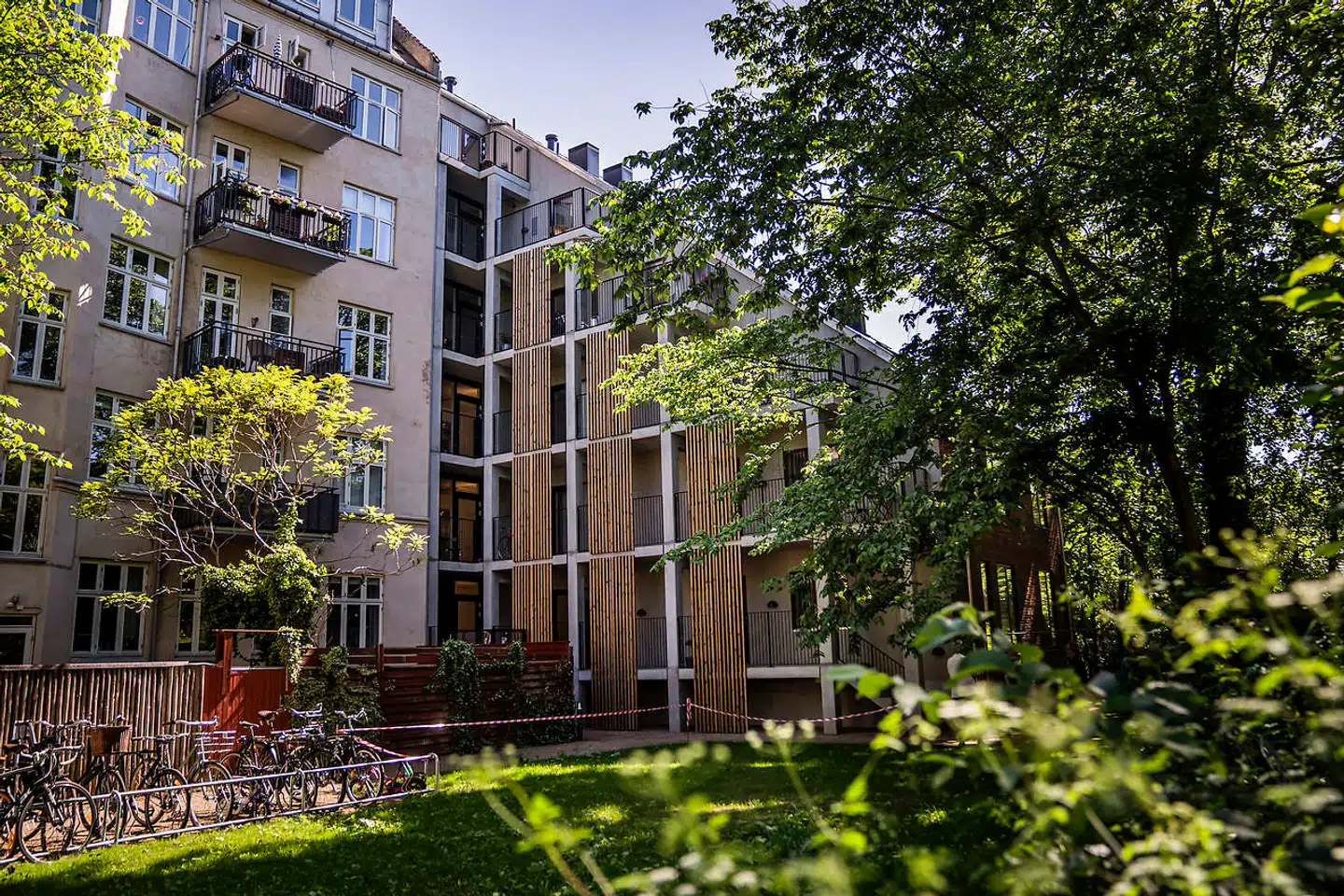 Mod gården står facaden i rå beton med fibercementplader og lamélinddækninger. Den lyse og mere porøse facade passer bedre til gårdmiljøet.