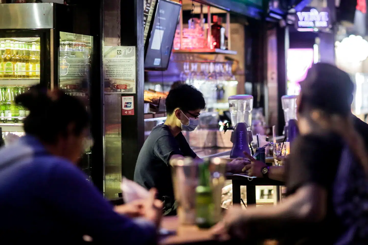 En mand med mundbind sidder i en bar i Singapore.